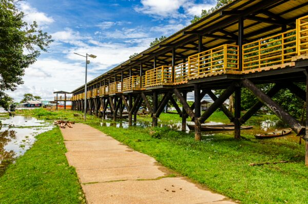 Vibrant yellow walkway stretches along the green landscape of Puerto Narino, Amazonas, Colombia, under a bright blue sky.