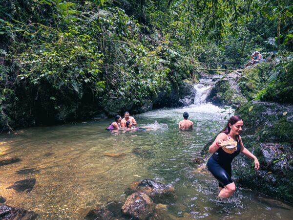 Visitors enjoy the tranquil Santa Rita Waterfalls in Salento, Quindío, Colombia, surrounded by lush greenery and clear waters.