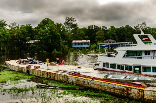 Colorful houses line the shore as a boat docks along the Amazon River in Leticia, Amazonas, Colombia, surrounded by lush greenery.