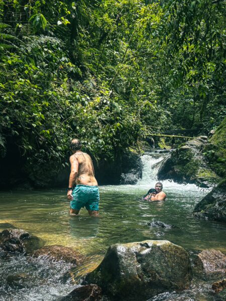 Refreshing experience at Santa Rita Waterfalls in Salento, Quindío, with two people enjoying the clear waters amidst lush greenery.