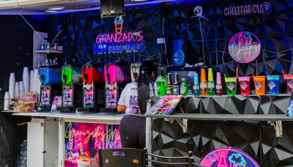 Colorful drinks line the counter of a vibrant bar in Comuna 13, Medellín, showcasing a lively atmosphere in Antioquia, Colombia.