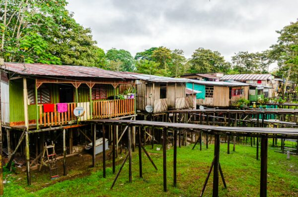 Colorful stilt houses with vibrant laundry hanging, surrounded by lush greenery in Leticia, Amazonas, Colombia.