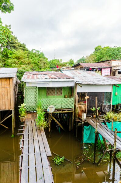 Colorful wooden houses on stilts reflect in the waters of Leticia, Amazonas, Colombia, surrounded by lush greenery.