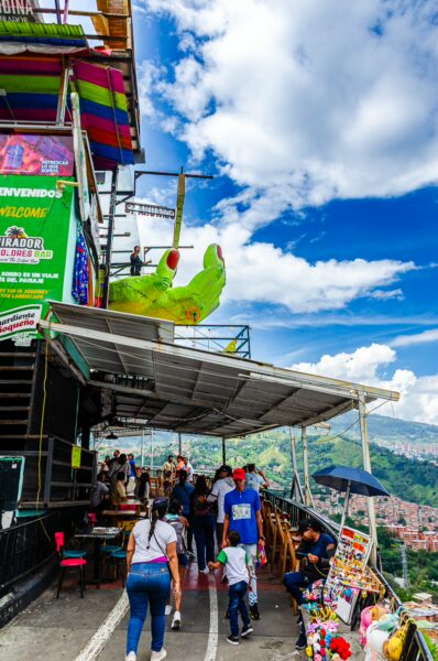 Vibrant street scene in Comuna 13, Medellín, with colorful murals, local vendors, and visitors enjoying the panoramic views.