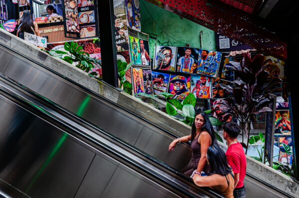 Visitors ride an escalator in Comuna 13, Medellín, surrounded by vibrant street art and lush plants adorning the walls.