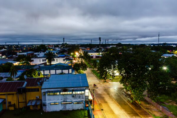 Sunset casts a warm glow over Parque Santander in Leticia, Amazonas, Colombia, highlighting vibrant buildings and lush trees.