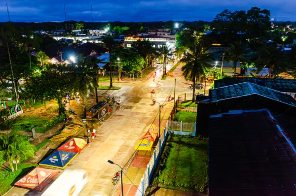 Vibrant street scene at Parque Santander in Leticia, Amazonas, Colombia, illuminated by colorful night lights and surrounded by lush greenery.