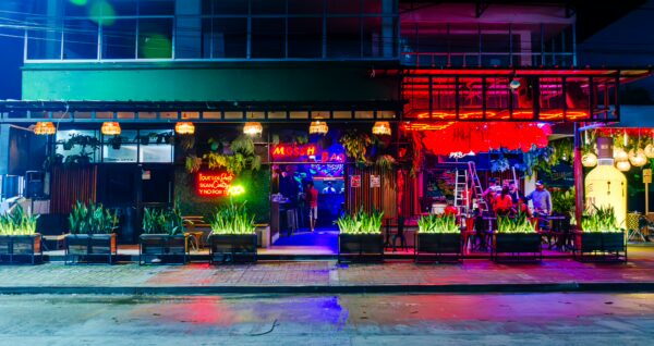 Vibrant nightlife scene in Leticia, Amazonas, Colombia, featuring colorful lights, open-air seating, and lush greenery.