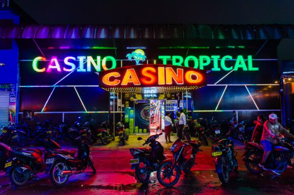Vibrant neon lights illuminate the Casino Tropical entrance in Leticia, Amazonas, Colombia, surrounded by parked motorcycles.
