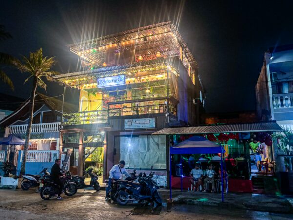 Colorful vibrant building illuminated at night, surrounded by palm trees and motorcycles, in Leticia, Amazonas, Colombia.