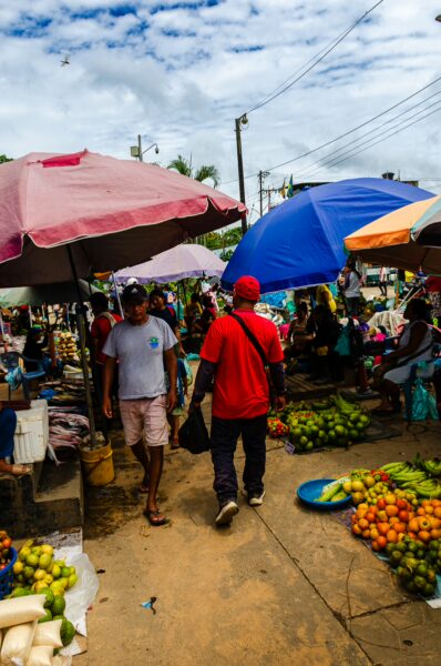 Vibrant market scene in Leticia, Amazonas, Colombia, featuring colorful umbrellas and a variety of fresh fruits and vegetables.