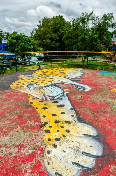 Vibrant mural of a jaguar paw on a colorful surface in Leticia, Amazonas, Colombia, with lush greenery in the background.