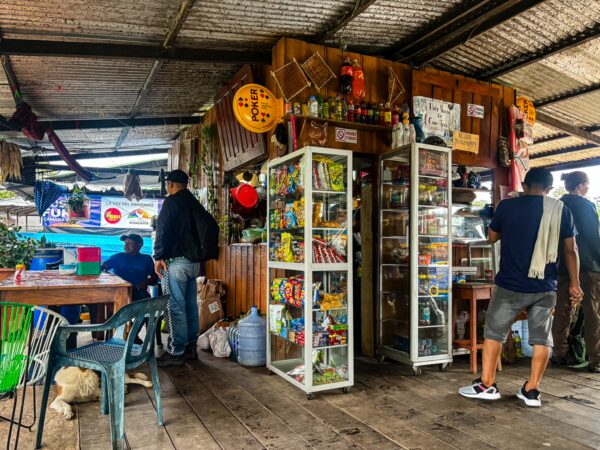 Local vendors and customers interact in a colorful market stall in Leticia, Amazonas, Colombia, showcasing diverse products and vibrant energy.