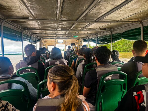 Passengers wearing life jackets sit inside a green ferry, traveling through the Amazon in Leticia, Amazonas, Colombia.