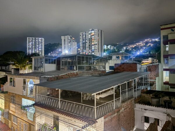 Cityscape of Bucaramanga at night, featuring illuminated high-rises and rooftops amidst a mountainous backdrop.