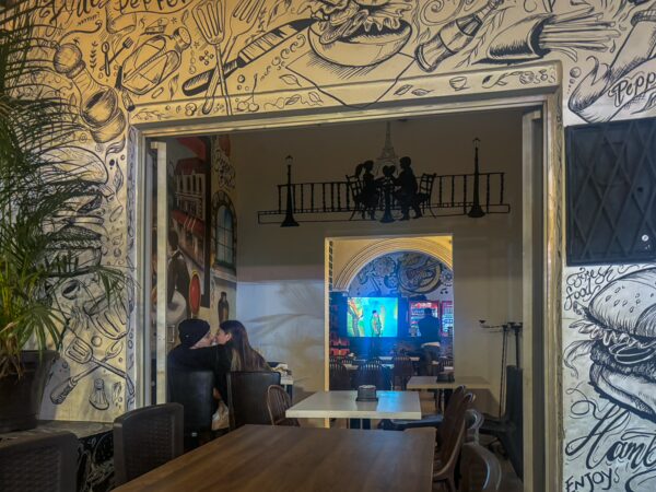 Cozy interior of a restaurant in Bucaramanga, featuring colorful murals, a dining table, and a view of patrons enjoying their meals.