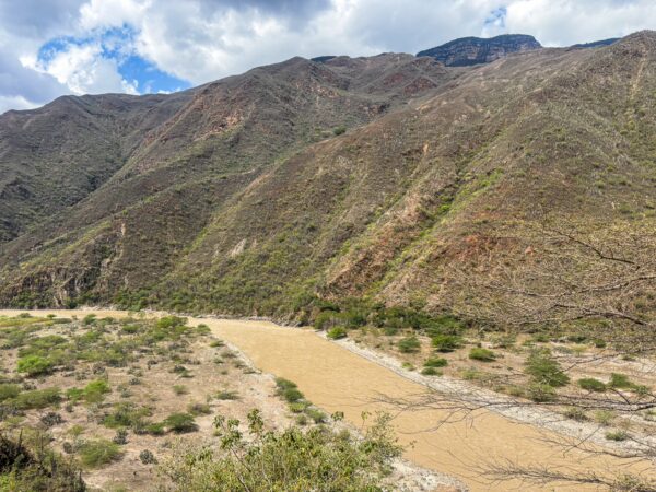 Chicamocha Canyon features rugged mountains with green vegetation and a winding river flowing through the arid landscape.