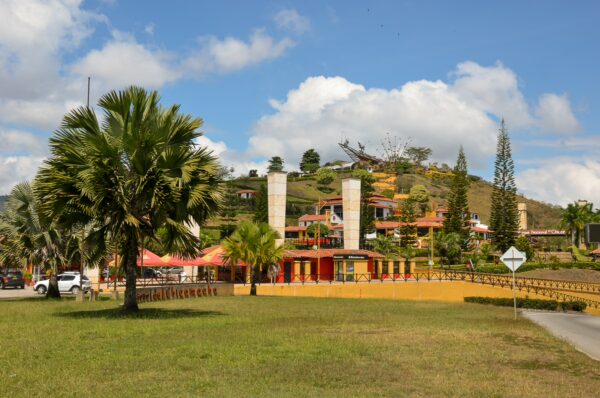 Colorful buildings and palm trees overlook the scenic Chicamocha Canyon in Santander, Colombia, under a bright blue sky.