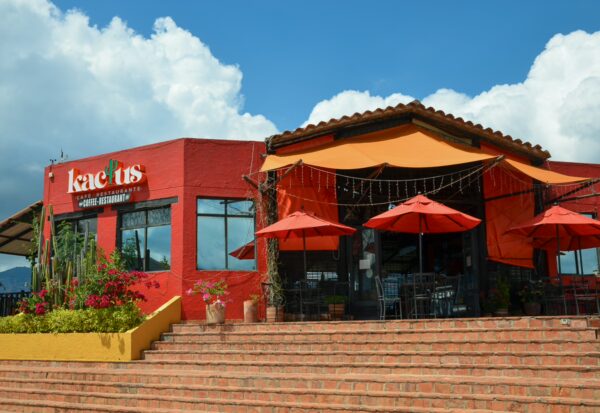 Red café and restaurant building at Chicamocha National Park, with orange umbrellas on a terrace and blue sky overhead