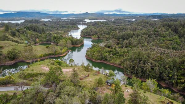Aerial view of lush green landscapes and winding rivers surrounding El Peñol Rock in Guatapé, Antioquia, Colombia.