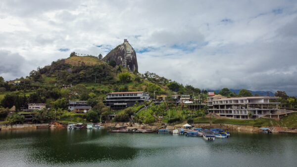 El Peñol Rock in Guatapé, Antioquia, Colombia, stands prominently above a peaceful lake surrounded by lush greenery and charming buildings.