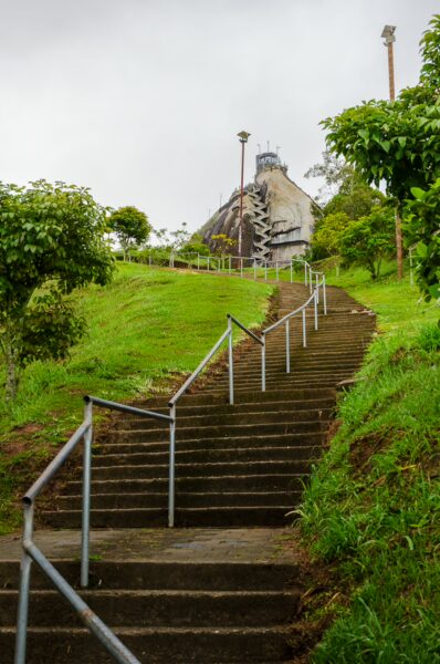 El Peñol Rock in Guatapé, Antioquia, Colombia, features a steep staircase leading up through lush greenery towards the summit.
