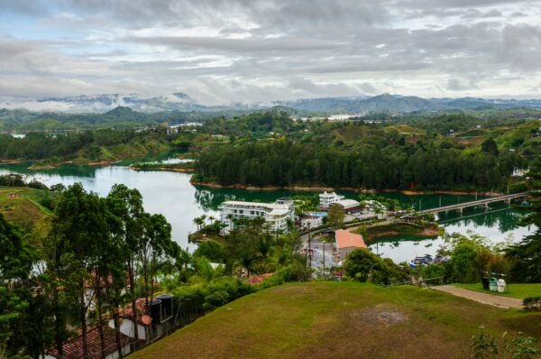 Scenic view of Guatapé, Antioquia, Colombia, showcasing lush greenery, tranquil waters, and a distant landscape under cloudy skies.