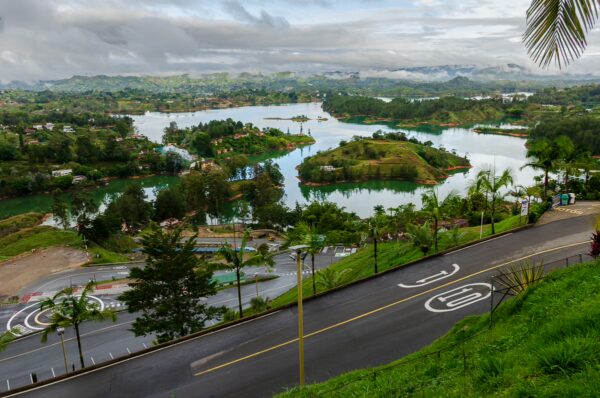 El Peñol, Guatapé, Antioquia, Colombia, showcases lush greenery, winding roads, and stunning lakes amid a cloudy sky.