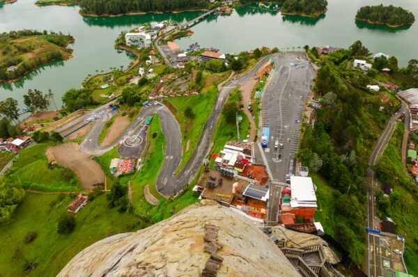 El Peñol Rock, Guatapé, Colombia showcases a panoramic view of winding roads, vibrant houses, and a serene lake surrounded by greenery.