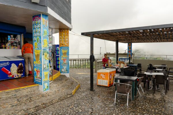 Colorful vendor stand and outdoor seating area at El Peñol Rock, Guatapé, Antioquia, Colombia, amid a misty landscape.