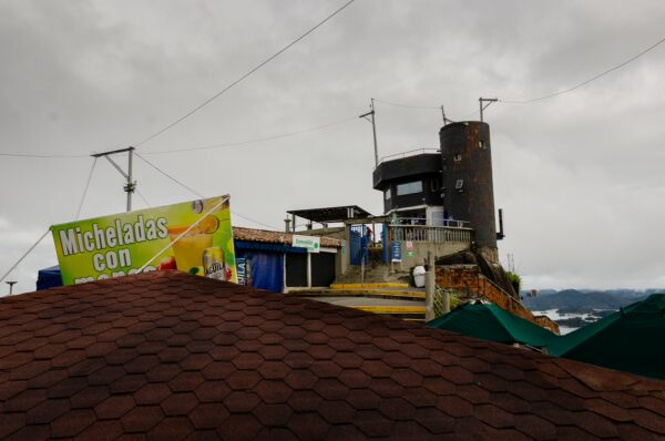 El Peñol, Guatapé, Antioquia: A view from the iconic rock structure surrounded by cloudy skies, with colorful market stalls below.