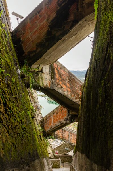 El Peñol Rock, Guatapé, Antioquia, Colombia, showcases moss-covered walls and rustic wooden beams in a narrow passageway.