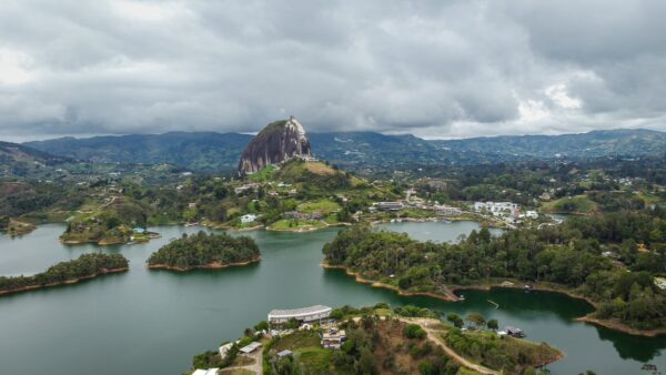 El Peñol Rock in Guatapé, Antioquia, Colombia, rises dramatically over lush green hills and serene lakes under a cloudy sky.