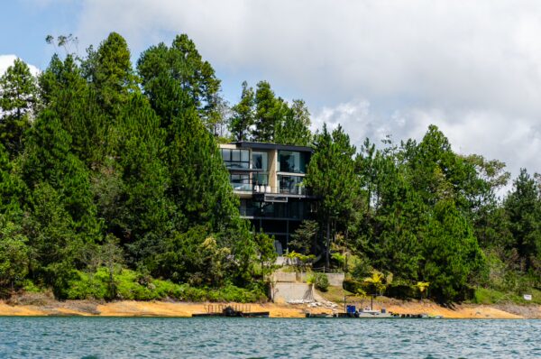 Guatapé Reservoir, Antioquia, Colombia features a modern building surrounded by lush green trees and a serene water view.