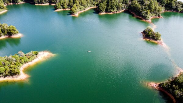 Guatapé Reservoir, Antioquia: Aerial view of serene turquoise waters surrounded by green islands and sandy shores.
