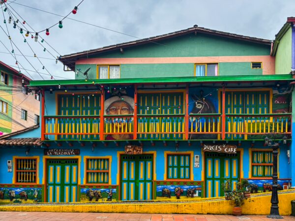Colorful colonial buildings with vibrant doors and balconies in Guatapé, Antioquia, surrounded by decorative lights and flowers.