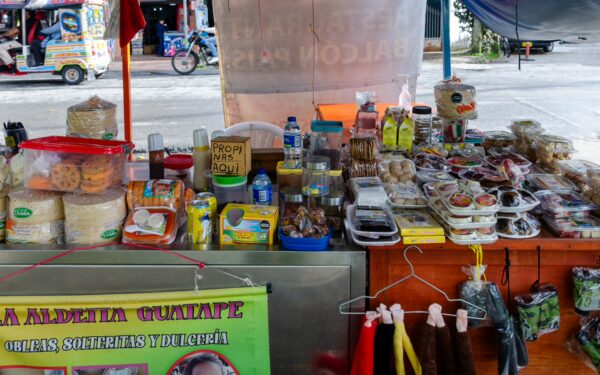 Vibrant food stall in Guatapé, featuring an array of snacks, beverages, and local treats under a colorful canopy.