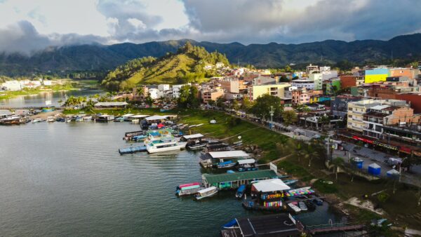 drone photo of Guatapé waterfront with floating docks, boats, and colorful buildings beside the reservoir