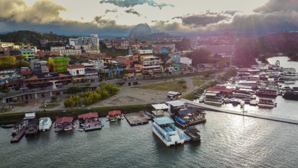 Aerial view of Guatapé with colorful buildings, a marina of boats, and the lush landscape surrounding the serene waters.
