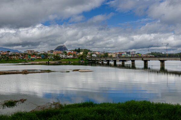 Guatapé–San Rafael Bridge crossing the reservoir with colorful town buildings and El Peñón in the distance
