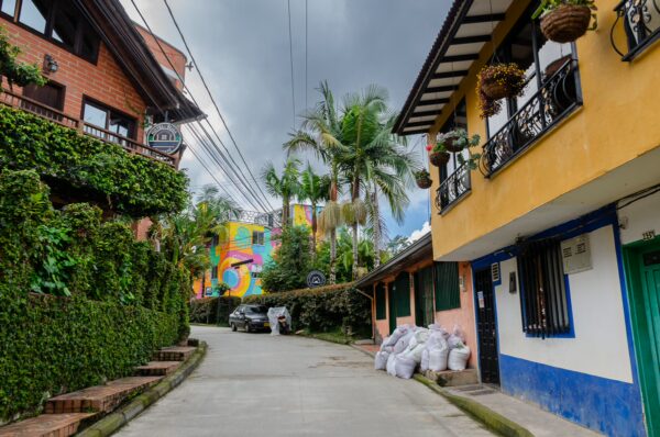 Colorful houses line a quiet street in Guatapé, Colombia, with lush greenery and vibrant murals enhancing the charming atmosphere.