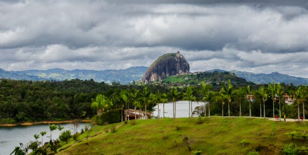 View over Guatapé’s reservoir with El Peñón de Guatapé rising in the distance under cloudy skies