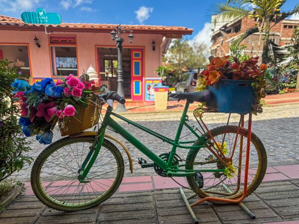 Decorated bicycle with flower-filled baskets in front of a colorful Guatapé building