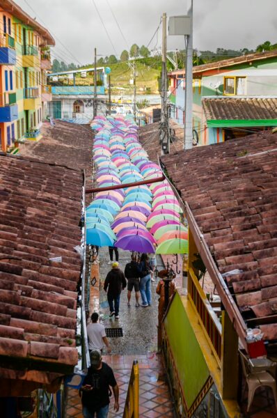 Colorful umbrellas line the cobblestone street in Guatapé, Colombia, creating a vibrant contrast against the quaint buildings.