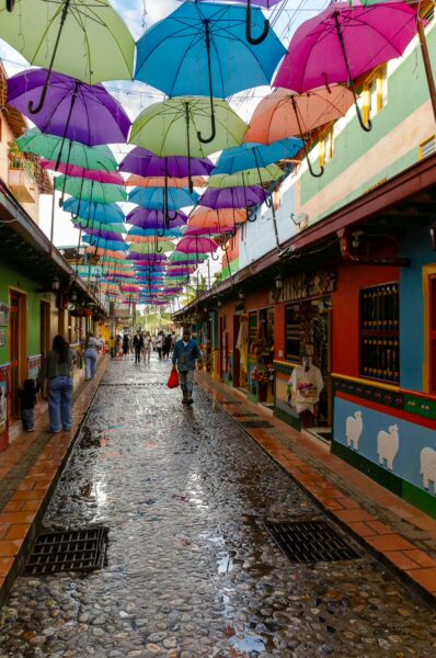 Colorful umbrella street in Guatapé with painted shopfronts and a cobblestone walkway