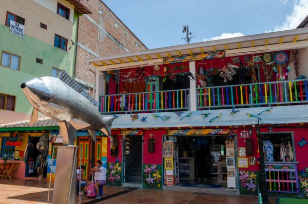 Brightly colored buildings and a large fish sculpture adorn Plazoleta de los Zócalos in Guatapé, showcasing vibrant local art.