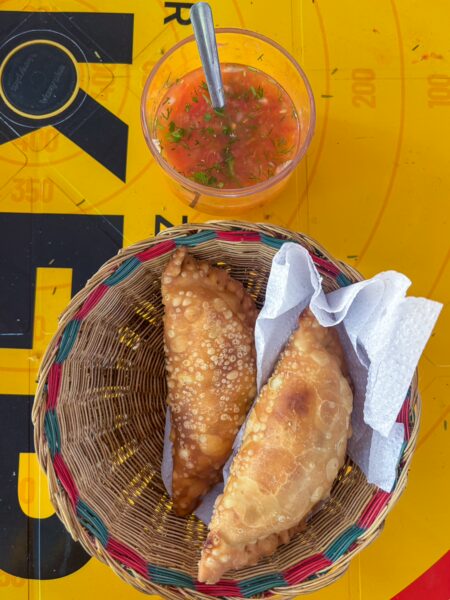 Basket of fried pastries with a small cup of salsa on a yellow café table in Jordán, Chicamocha Canyon