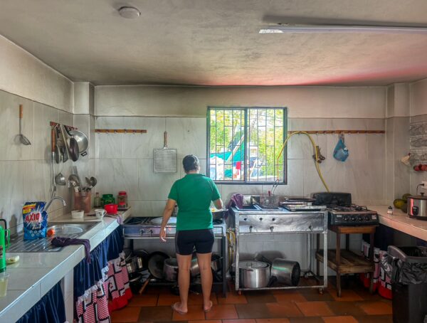 A busy kitchen in Santander, Colombia, featuring cooking equipment, utensils, and a person preparing food. Natural light streams in through the window.