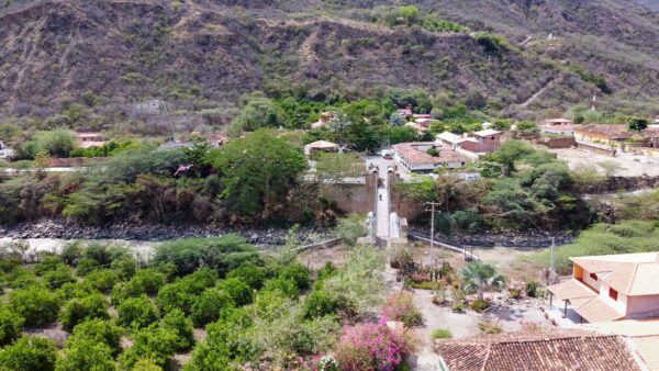 Scenic view of Jordan, Santander, Colombia, showcasing a lush landscape with homes, a bridge, and surrounding mountains.