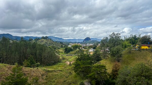 Mirador San Jose, Guatapé, Antioquia, Colombia features a lush green landscape with rolling hills, cloudy skies, and distant mountains.